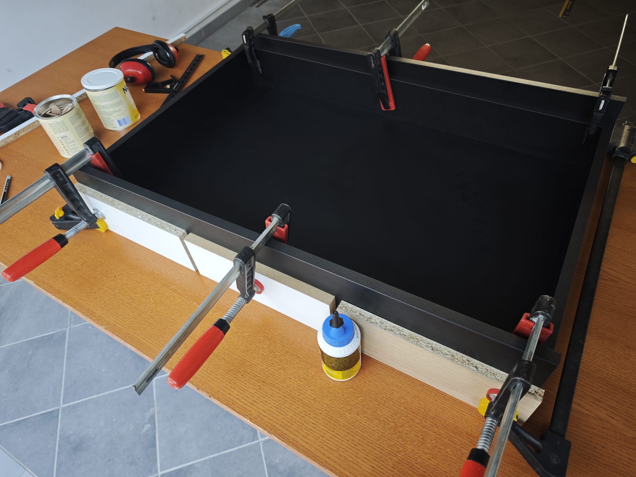 The dartboard section glued and held square by bar clamps while the joints set