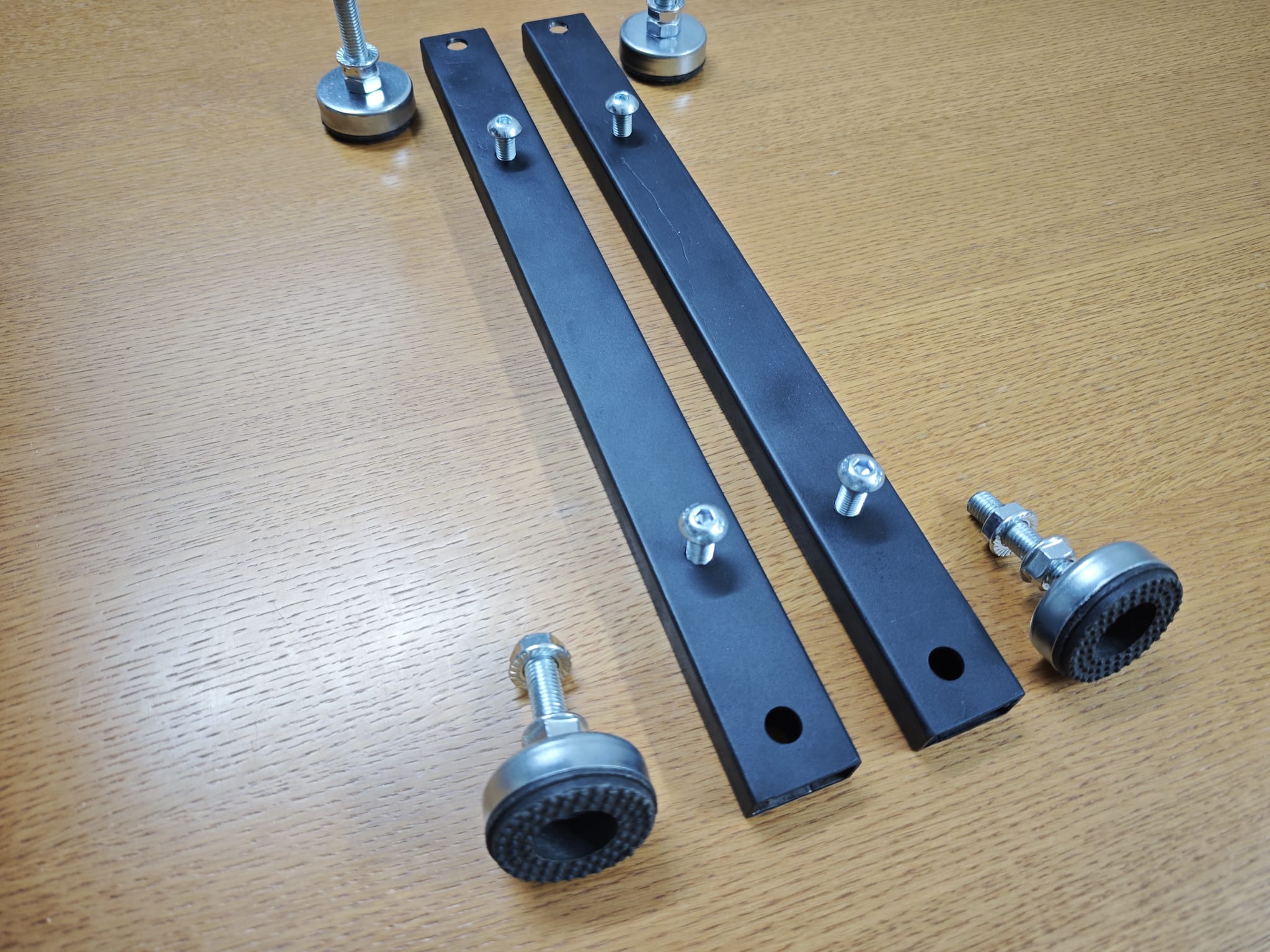 Adjustable feet and black steel support rails for the Vulcano base laid out on a table